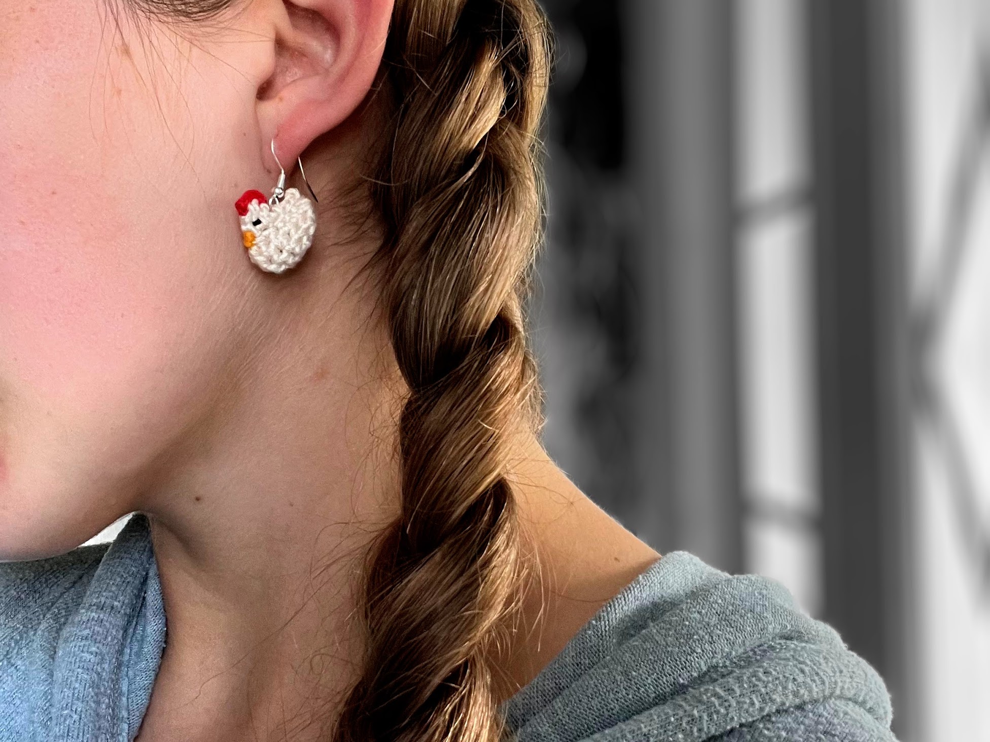 Amigurumi Chicken Earring Completed using Crochet Pattern Hanging from Ear with a lovely braid next to it.