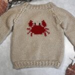 Crabby Baby Sweater made using the Crochet Pattern listed featuring a super cute red crab on a tan sweater